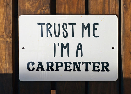 a white sign that says trust me i'm a carpenter