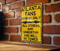 a yellow atlanta fans parking only sign on a brick wall