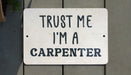 a white sign that says trust me i'm a carpenter