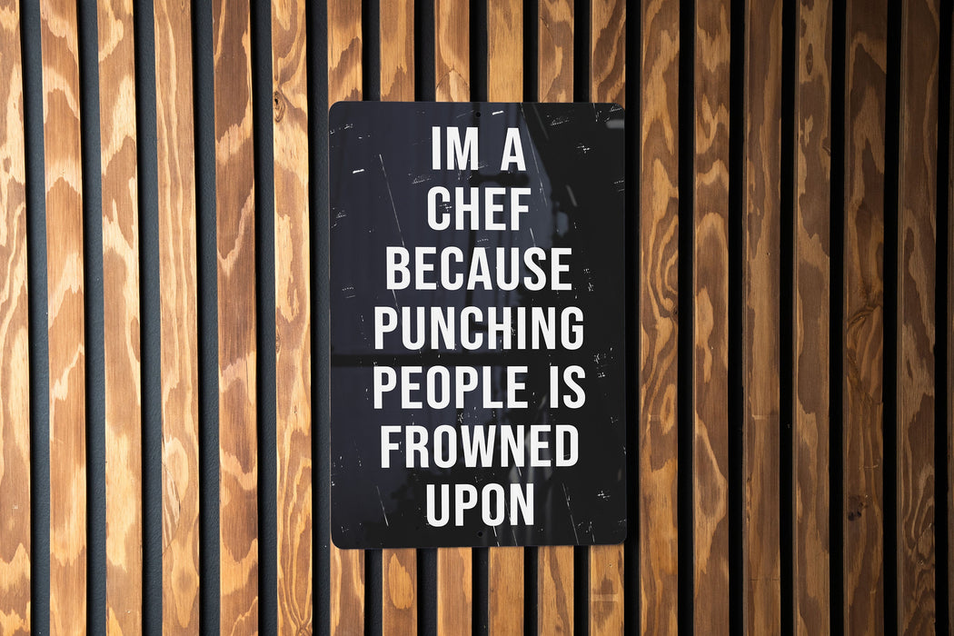a sign on a wooden wall that says i'm a chef because punching people