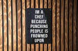 a sign on a wooden wall that says i'm a chef because punching people