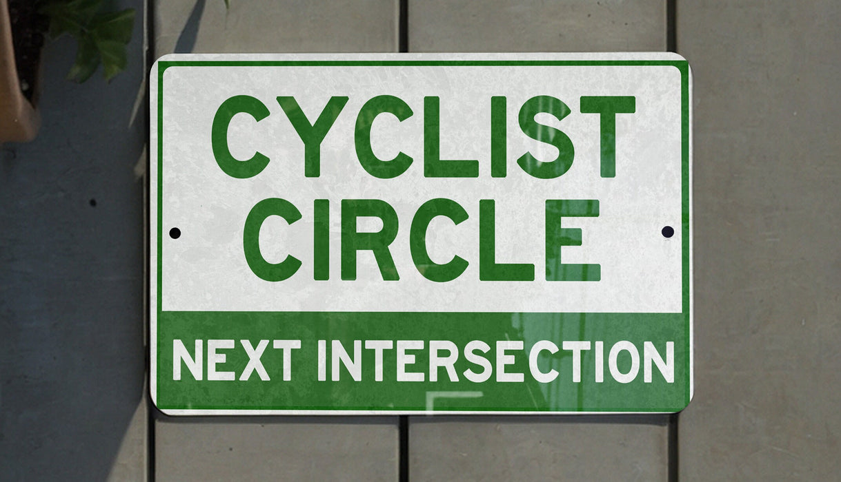 a green and white sign that says cyclist circle next intersection