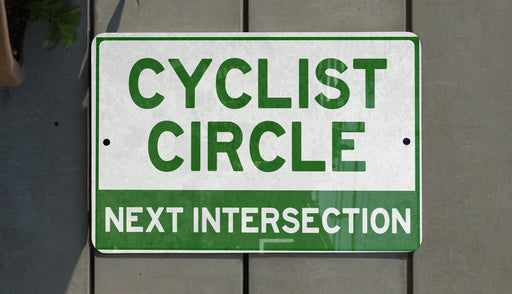 a green and white sign that says cyclist circle next intersection