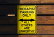 a yellow sign on a wooden wall that says therapst parking only all