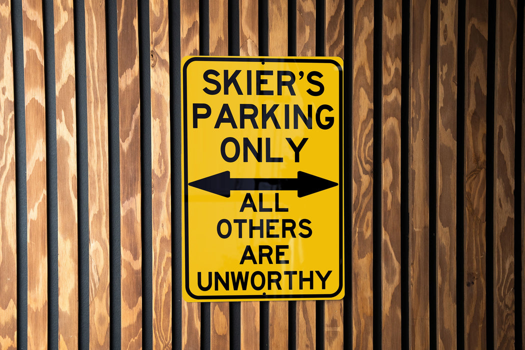 a yellow sign on a wooden fence that says skier's parking only all others