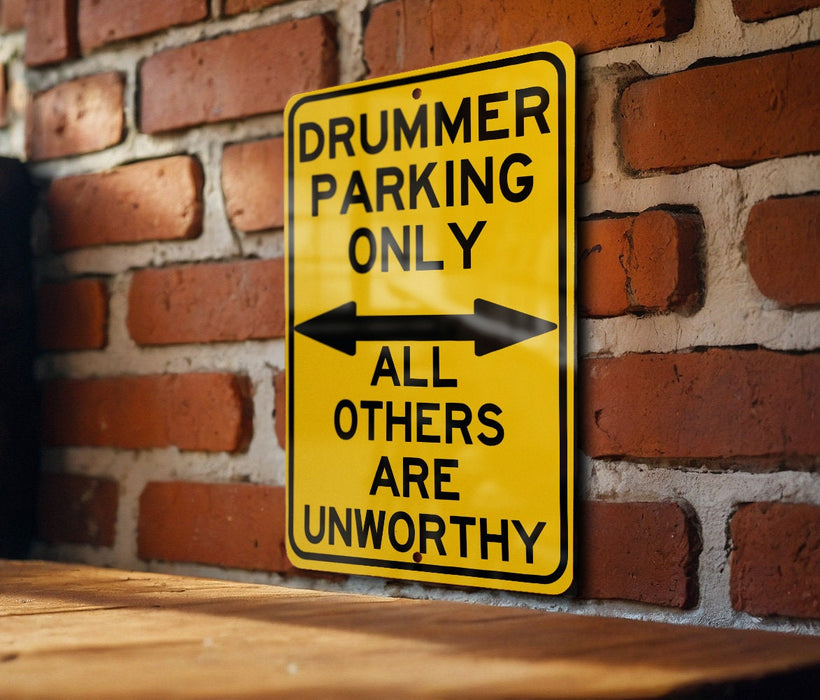 a yellow sign on a brick wall that says drummer parking only all others are un