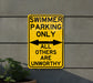 a yellow swimming only sign hanging on the side of a building