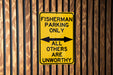a yellow sign on a wooden fence that says fisherman parking only all others are un