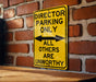 a yellow sign on a brick wall that says director parking only all others are un