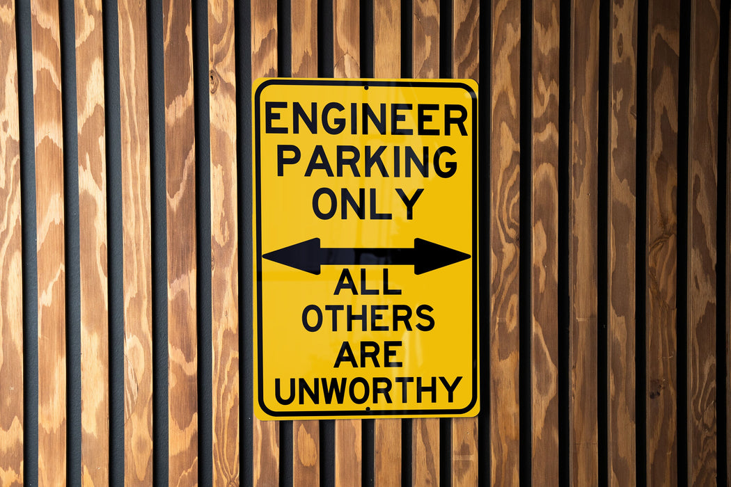 a yellow sign on a wooden fence that says engineer parking only all others are un