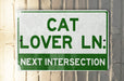a green and white sign that says cat lover ln next intersection