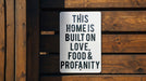 a sign on a wooden fence that says this home is built on love, food