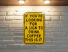 a yellow sign that says if you're looking for a sign to drink coffee
