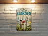 a picture of a garden sign hanging on a brick wall