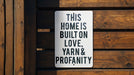 a sign that says this home is built on love, yarn and propanety