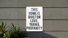 a sign on a wall that says this home is built on love, yarn and