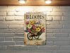 a brick wall with a picture of a wheelbarrow with flowers on it