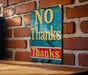 a no thanks sign on a brick wall