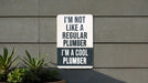 a sign on a wall that says i'm not like a regular plumber