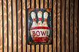 a bowling sign hanging on a wooden wall