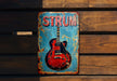 a red and blue guitar sign on a wooden wall