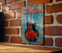 a red electric guitar on a blue sign on a brick wall