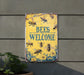 a sign that says bees welcome hanging on the side of a building