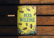 a sign that says bees welcome on a wooden bench