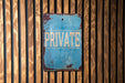 a blue private sign on a wooden wall