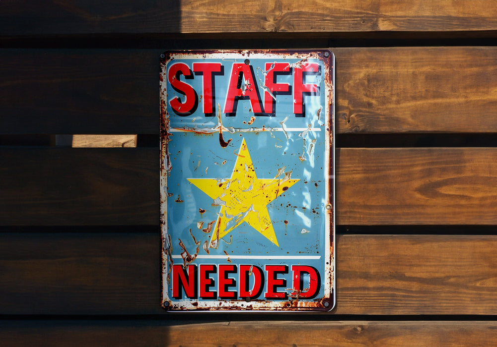 a sign on a wooden wall that says staff needed
