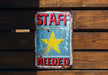 a sign on a wooden wall that says staff needed