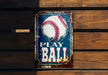 a metal sign with a baseball on it