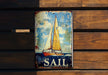 a sail sign hanging on a wooden wall