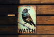 a bird sitting on top of a sign on a wooden wall