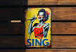 a sing sign is hanging on a wooden wall