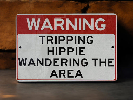 a red and white sign warning of tripping hippie wandering the area