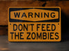 a yellow warning sign that says, warning don't feed the zombies