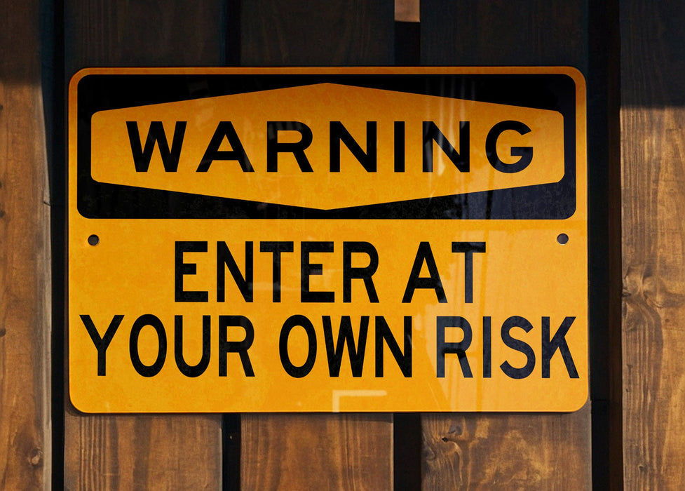 a yellow and black sign on a wooden fence