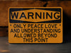 a warning sign on a wall that says, warning only peace love and understanding