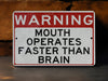 a red and white sign warning of mouth operates faster than brain
