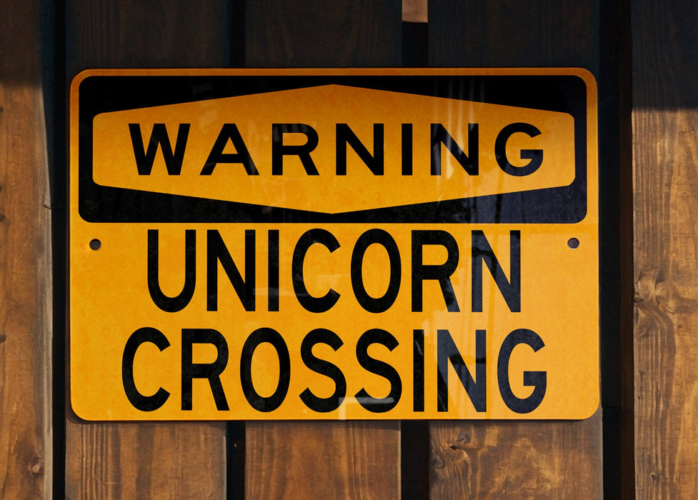 a yellow street sign on a wooden fence