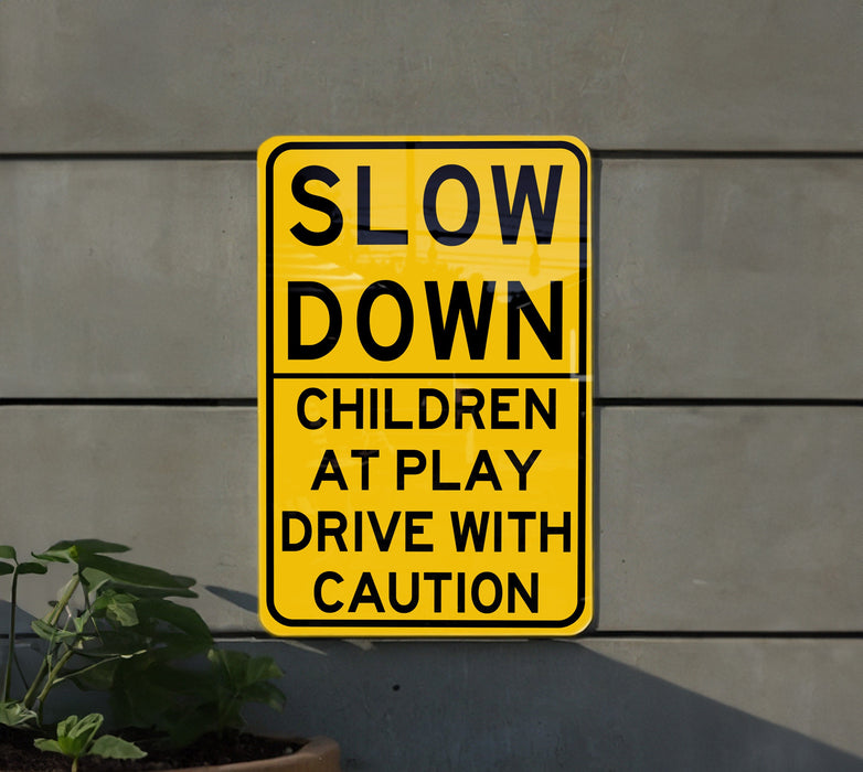 a slow down children at play sign next to a plant