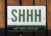 a green and white sign that says shh no one cares