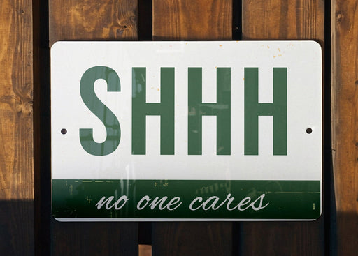 a green and white sign that says shh no one cares