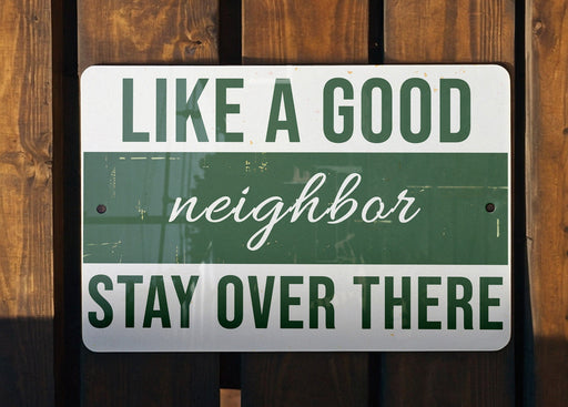 a green and white sign that says like a good neighbor stay over there