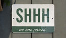 a green and white sign that says shh no one cares