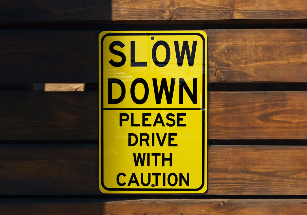 a yellow slow down sign on a wooden wall