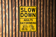 a yellow slow down sign on a wooden wall