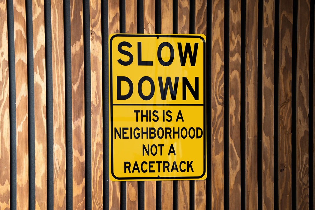 a yellow slow down sign on a wooden fence