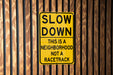 a yellow slow down sign on a wooden fence